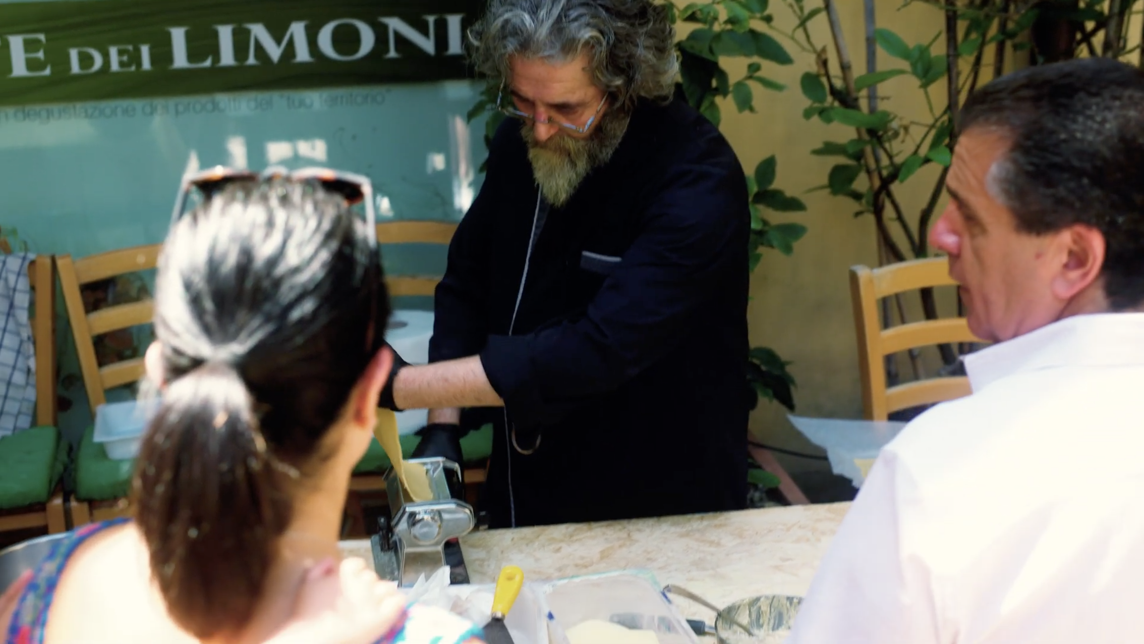 Participants seated around a table during a Lucca Cooking Class introduction, with chefs welcoming guests in an outdoor setting.